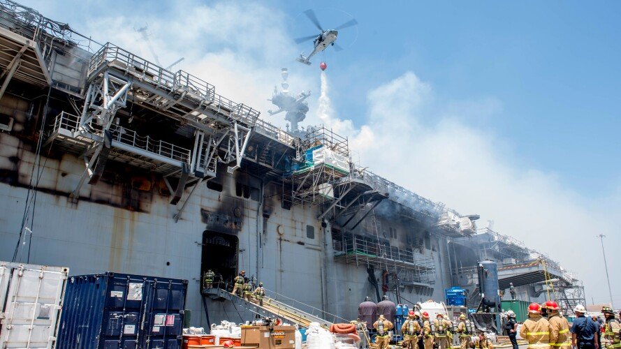A helicopter from the "Merlins" of Helicopter Sea Combat Squadron 3 fights a fire sweeping the amphibious assault ship Bonhomme Richard (LHD 6) on July 13, 2020, a day after the blaze erupted on the vessel moored pier side at Naval Base San Diego. US Navy photo by Mass Communication Specialist 1st Class David Mora Jr.