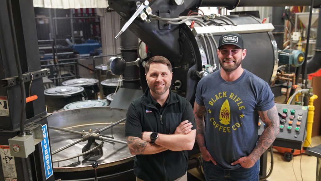Black Rifle Coffee Company CEO Evan Hafer and Executive Vice President Mat Best stand in front of a roaster at the roasting facility in Salt Lake City. Photo courtesy of Black Rifle Coffee.