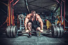 Powerlifter with strong arms lifting weights. Adobe Stock Image.