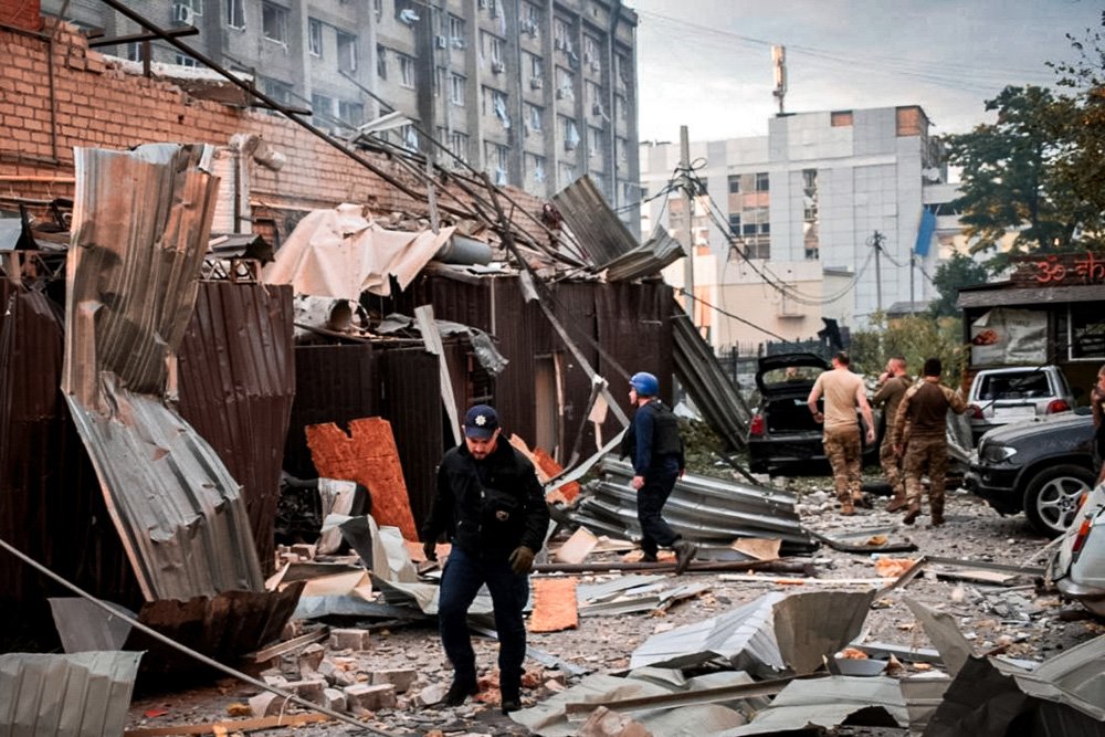 A police officer and a rescue worker walk in front of a restaurant RIA Pizza destroyed by a Russian attack in Kramatorsk.