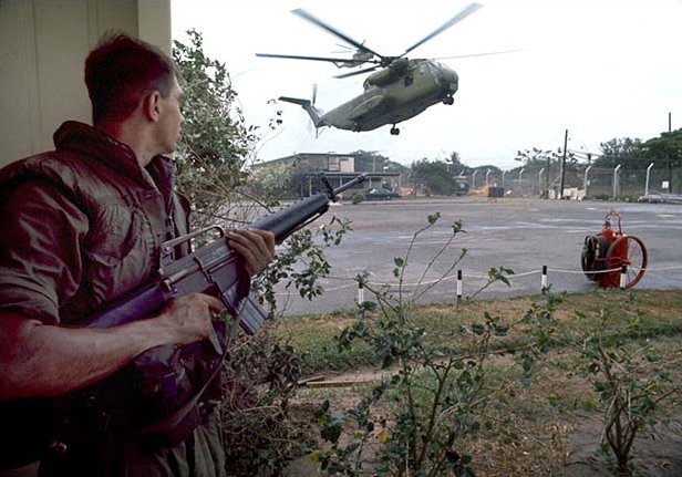 United States Marine Private First Class Forrest M. Turner Jr. provides security as two Sikorsky CH-53 helicopters land at the Defense Attaché Office compound during Operation Frequent Wind, April 29, 1975. Military helicopters dropped the ground security component at landing zones. Once on the ground they set up security positions. Photo by Dirck Halstead/released via Wikipedia.