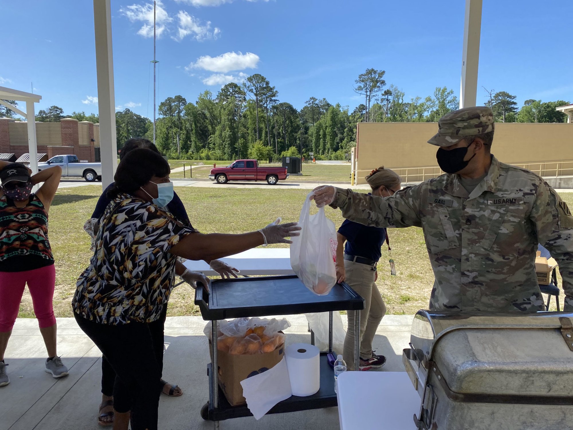 Staff Sgt. Josua Garo hands off a bagged lunch to a Diamond Elementary School food service staff member April 29 on Fort Stewart. Garo is a volunteer for the DoDEA Fort Stewart School Meal Program during the COVID-19 pandemic. He and nine other Soldiers are volunteering across post, helping to provide services to the community. Photo by Spc. Noelle Wiehe/Fort Stewart Public Affairs Office. coffee or die