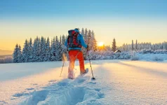 Snowshoe walker running in powder snow with beautiful sunrise light. Outdoor winter activity and healthy lifestyle