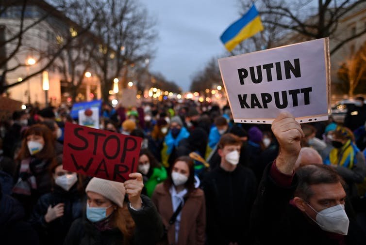 Pro-Ukraine demonstrators hold flags and placards during a demonstration in front of the Russian embassy in Berlin on Feb. 22, 2022. John Macdougall/AFP via Getty Images and The Conversation.