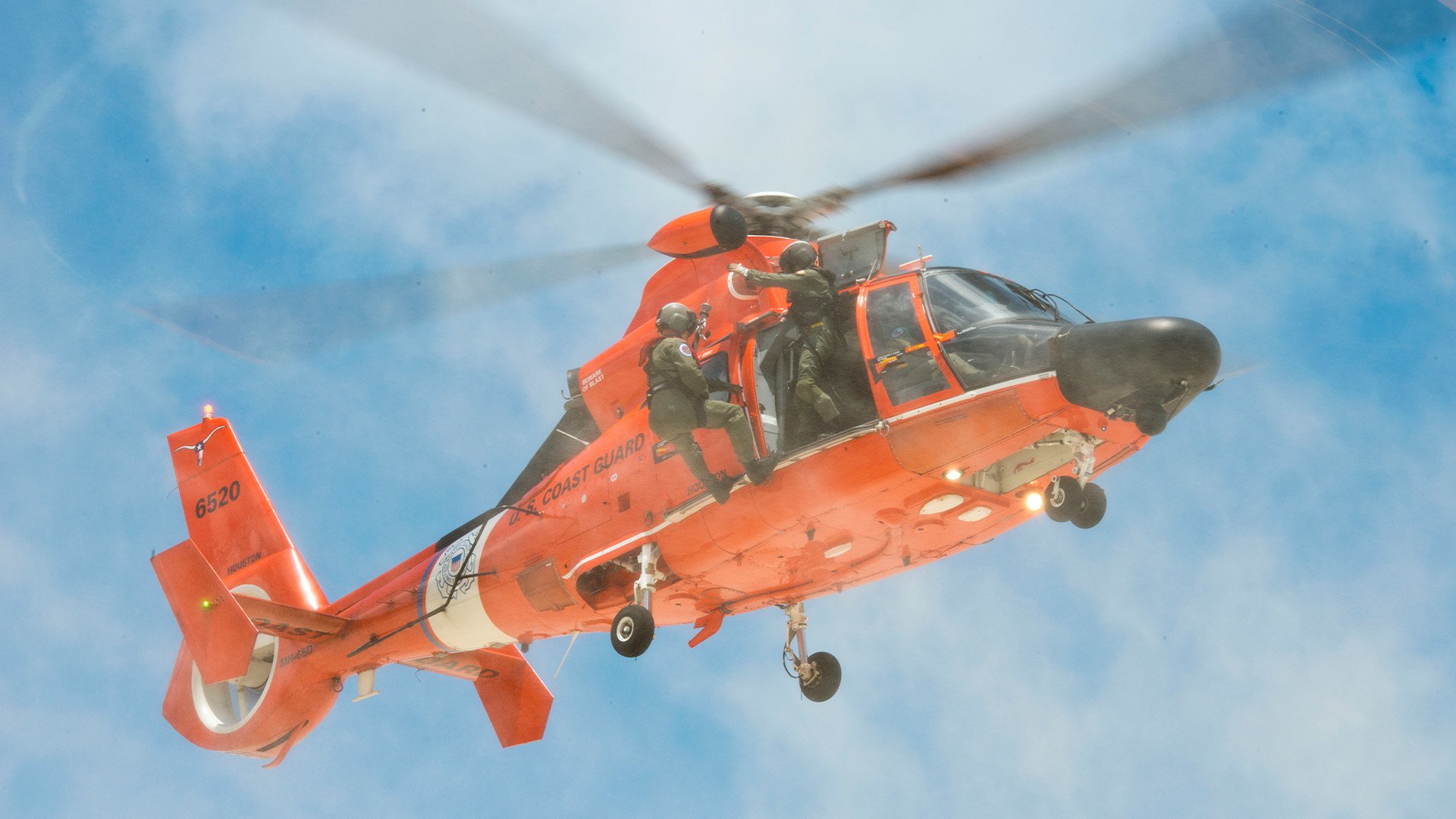 A US Coast Guard crew from Air Station Houston hovers over San Luis Pass, May 24, 2014, part of an effort by first responders to keep people from trying to swim in treacherous waters that had claimed four lives in 2013. US Coast Guard photo.