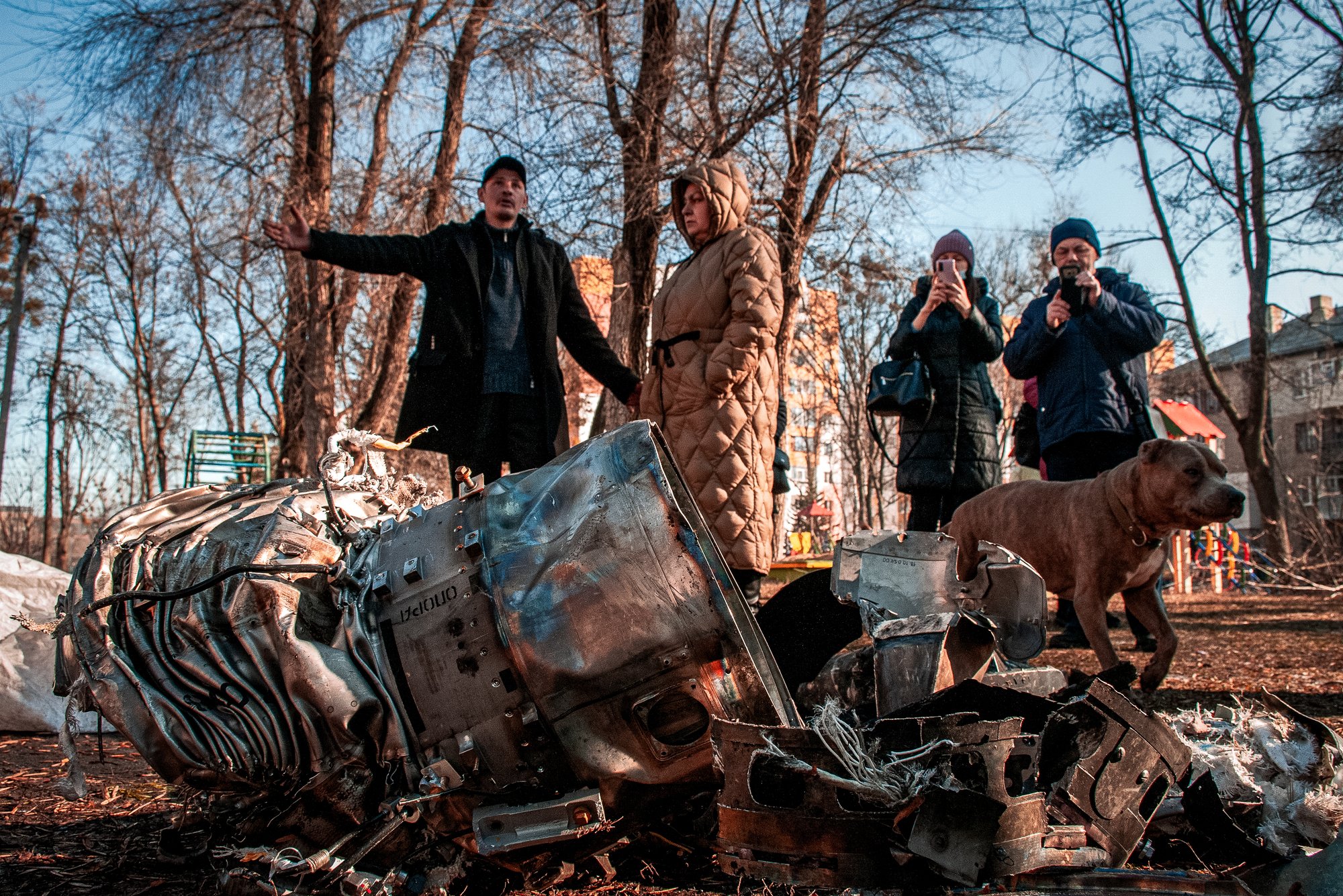 People stand next to fragments of military equipment on the street in the aftermath of an apparent Russian strike in Kharkiv in Kharkiv, Ukraine, Thursday, Feb. 24, 2022. Russian troops have launched their anticipated attack on Ukraine. Big explosions were heard before dawn in Kyiv, Kharkiv and Odesa as world leaders decried the start of an Russian invasion that could cause massive casualties and topple Ukraine's democratically elected government. (AP Photo/Andrew Marienko )