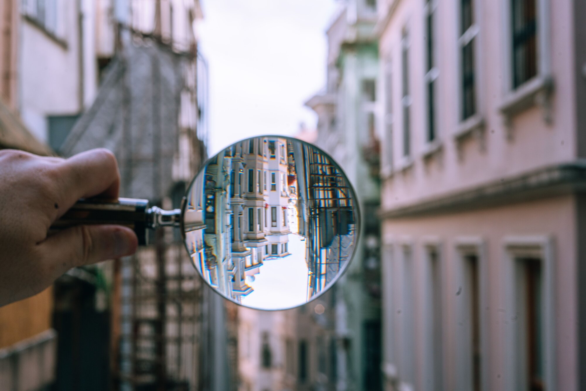 Close-up of a magnifying glass highlighting the details of buildings in a narrow alleyway, symbolizing the precision and focus required in Data Analytics within the financial industry.