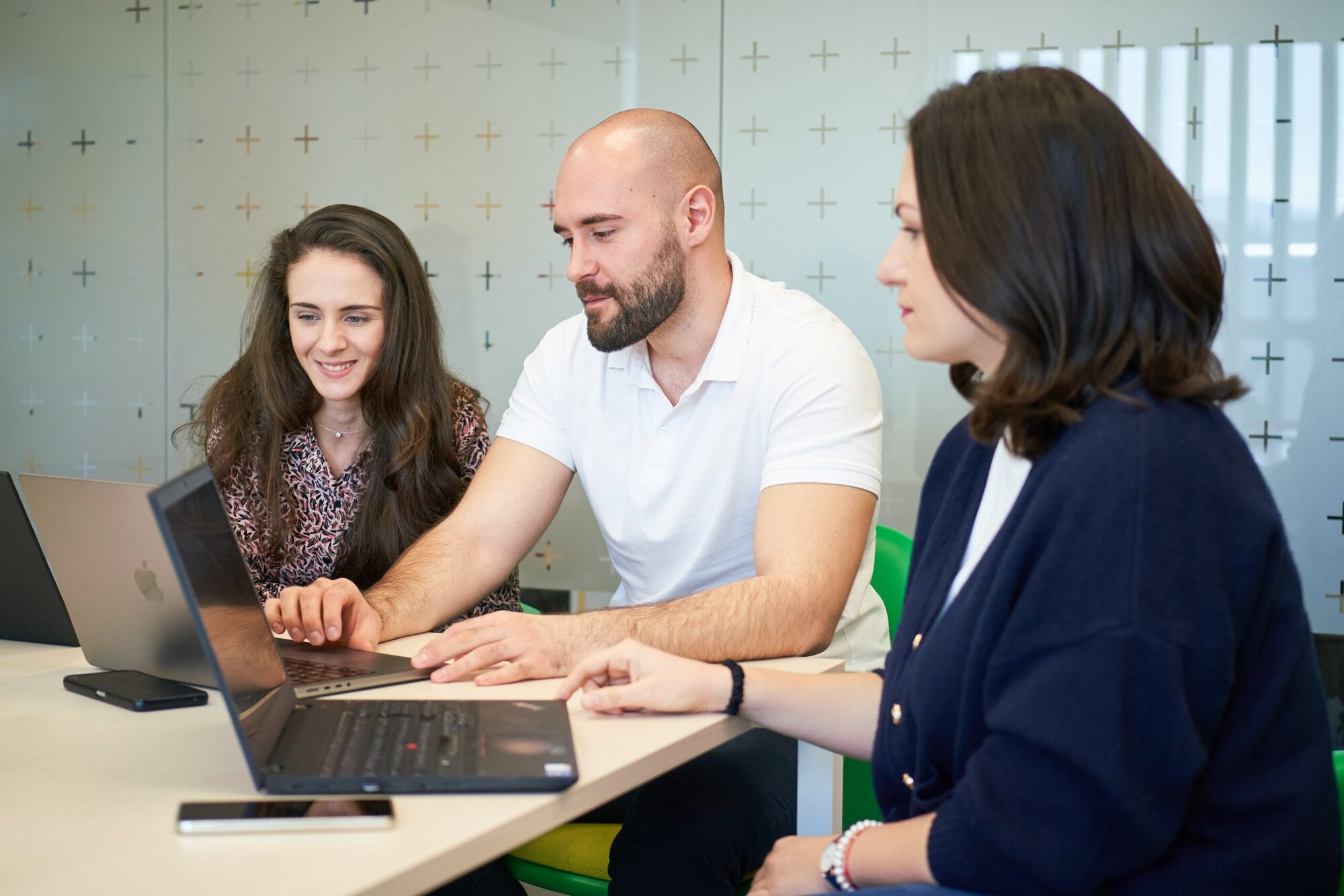 Three colleagues working on a laptop in an office