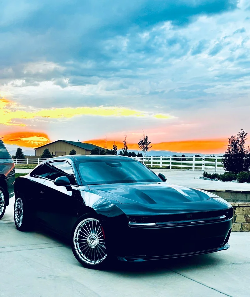 Black performance coupe with polished wheels at sunset