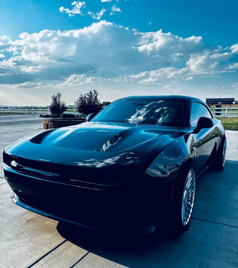 Black performance coupe reflecting clouds at a driveway