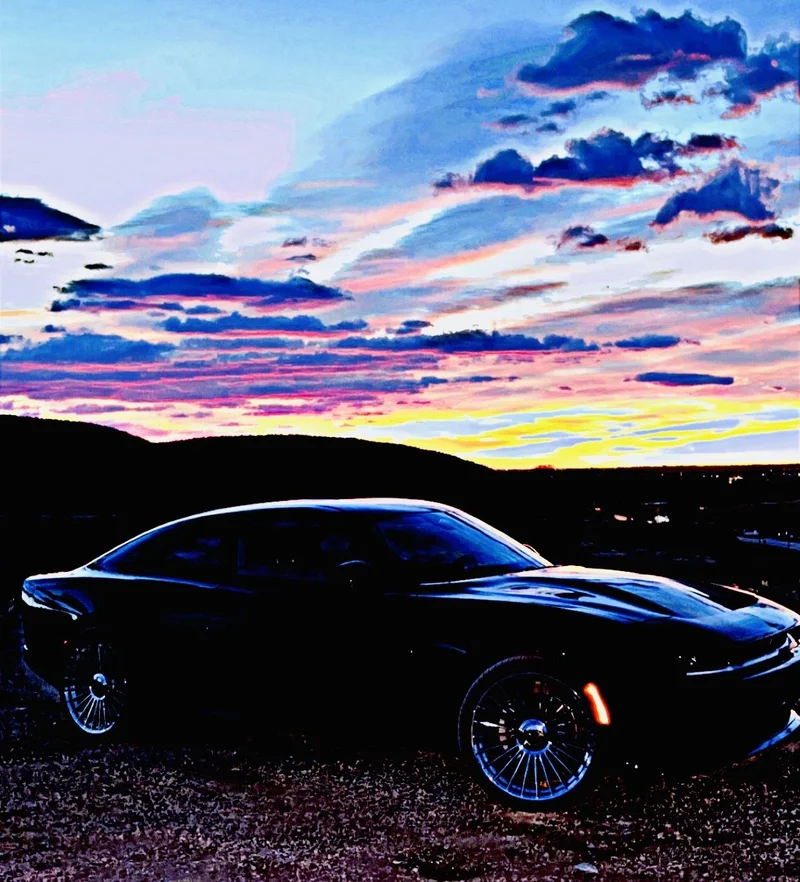 Black performance coupe parked beneath a colorful Colorado sunset