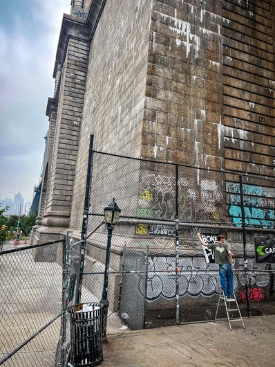 Artsy shot of Peter posting up banners with the city in the background. Chef's kiss

<!--damnamnyc23-day2-->