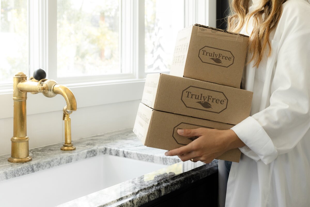 Woman holding Truly Free Home product boxes. 