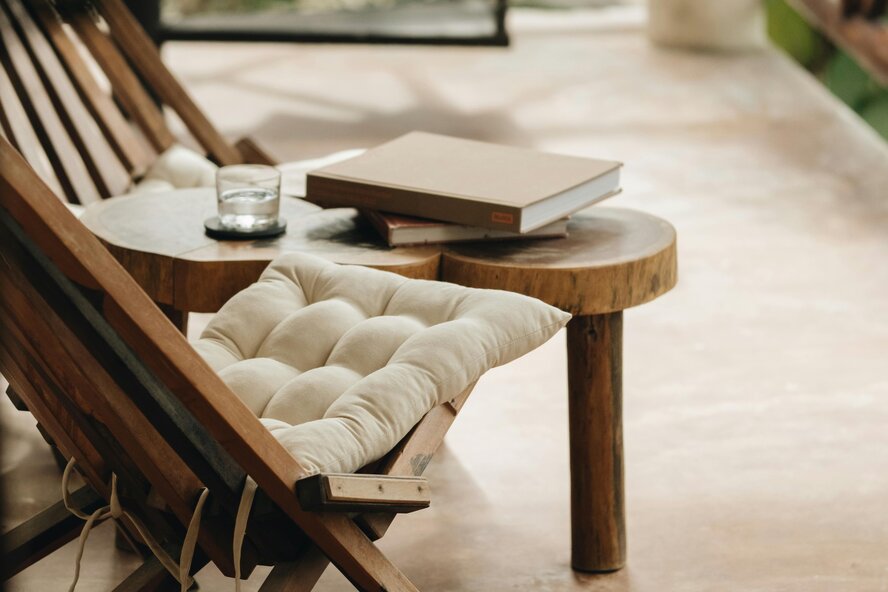 Two patio chairs with cushions and a coffee table with books. 