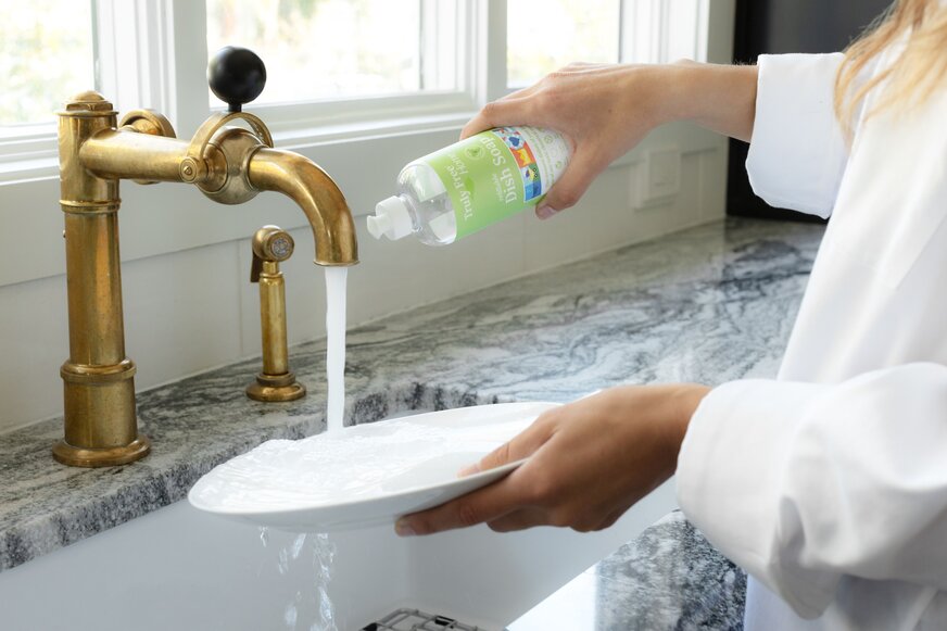 Woman washing dishes with Truly Free Home Non-Toxic Dish Soap.