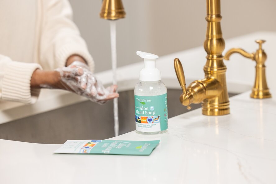 Person washing their hands with Truly Free Home Aloe Hand Soap.