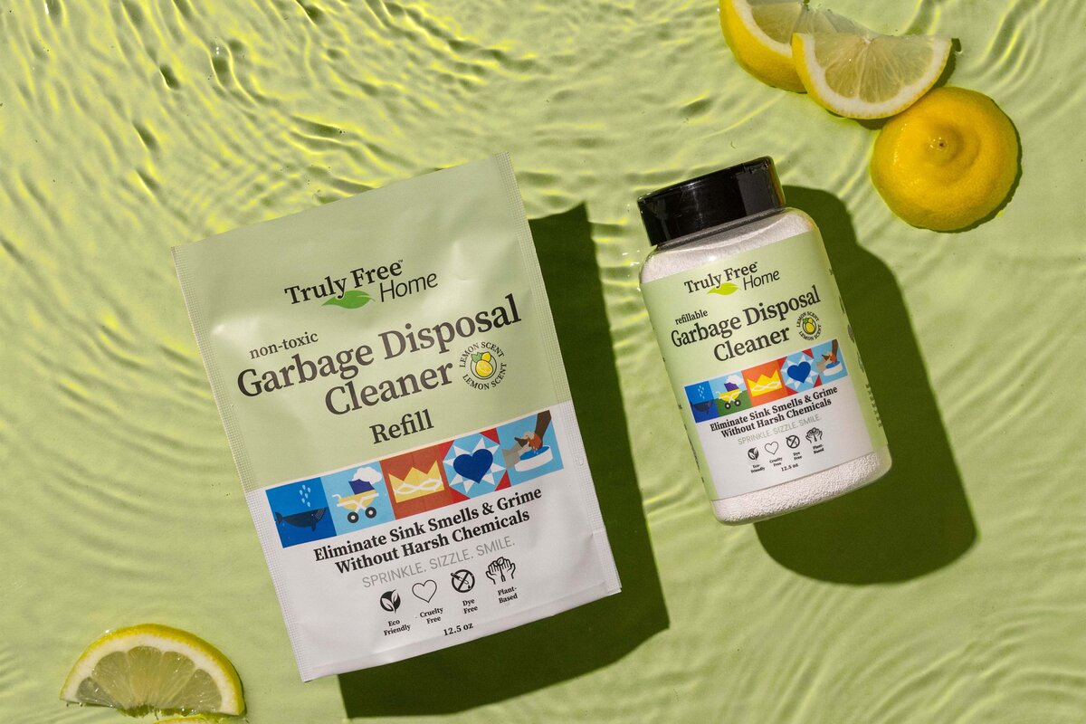 Flat lay of garbage disposal cleaner and refill pack in water surrounded by lemons