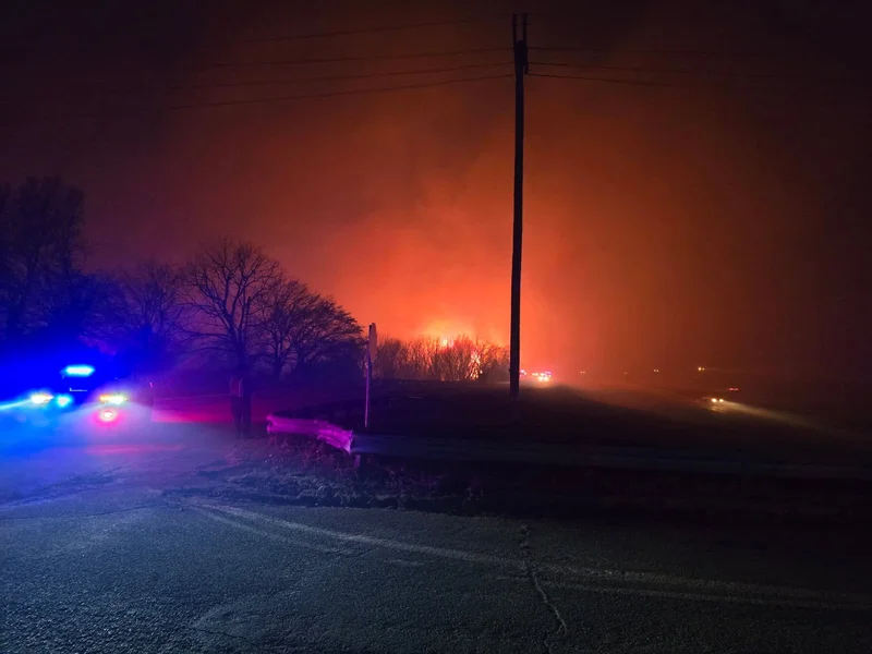 Emergency vehicle lights beside a field fire at night