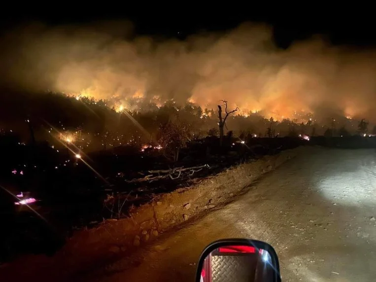 Night brush fire on a hillside above a dirt road