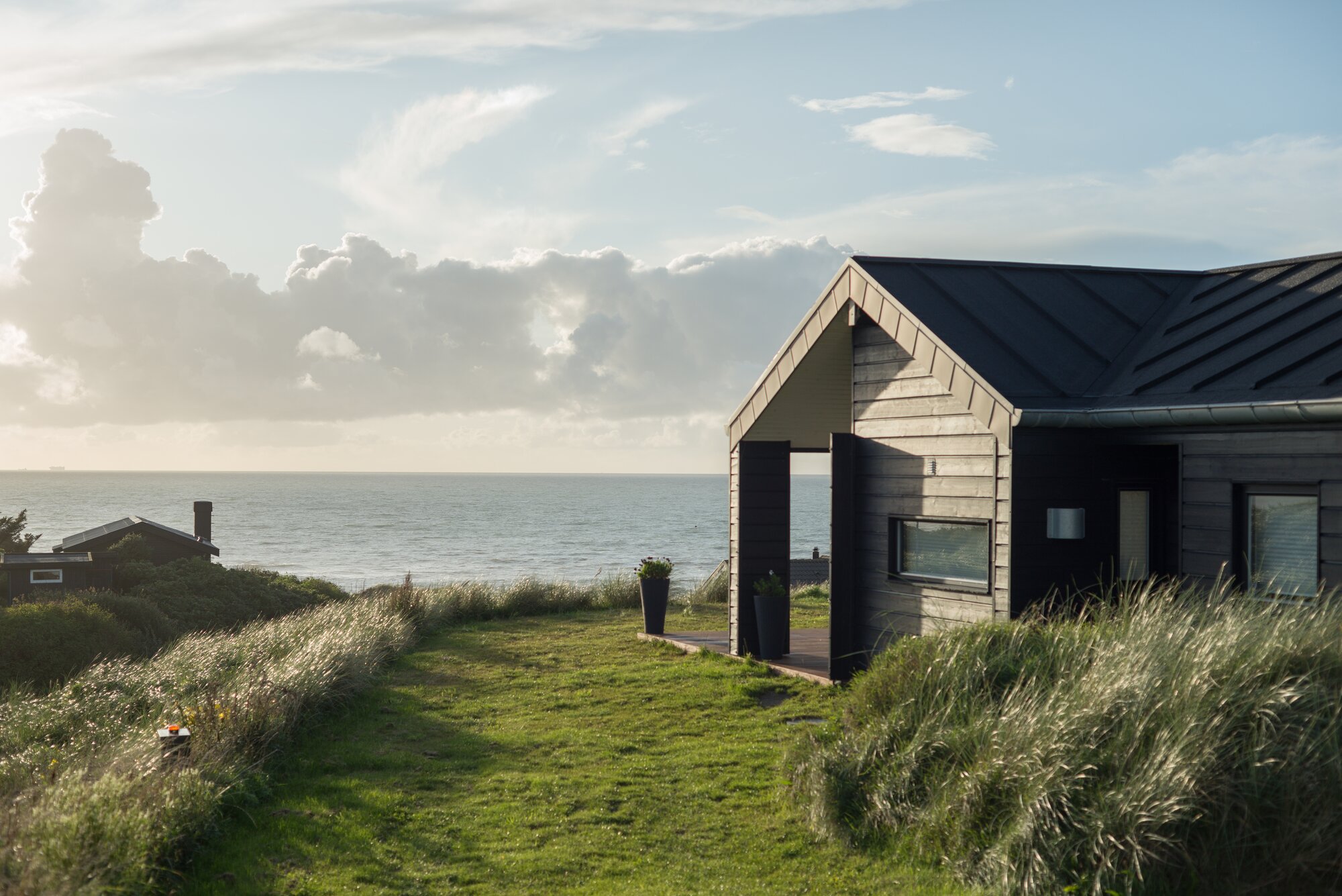 Sommerhus med havudsigt omgivet af klitgræs og natur tæt på stranden.