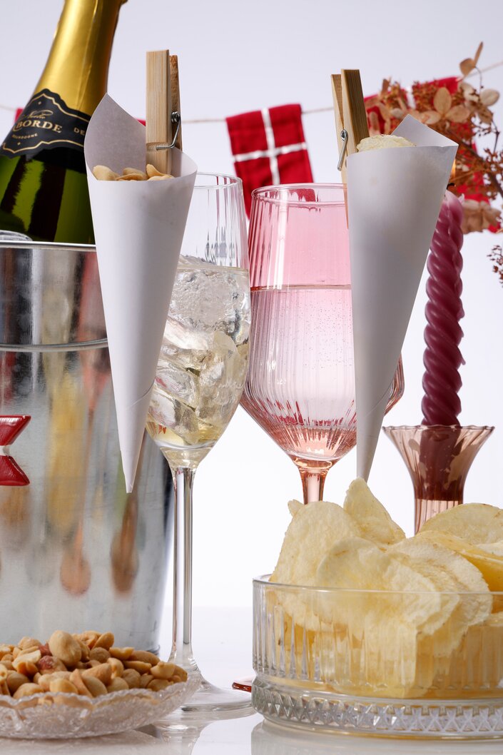 Festbord med champagne, snacks og røde flag til hyggelig fejring.