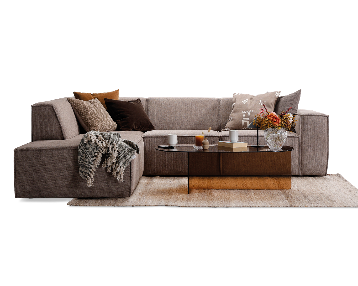 Quadrato modulsofa i beige møbelstof. Opstilling med open end, og pyntet med røgfarvet glasbord, beige gulvtæppe, samt puder og nips i jordfarver.