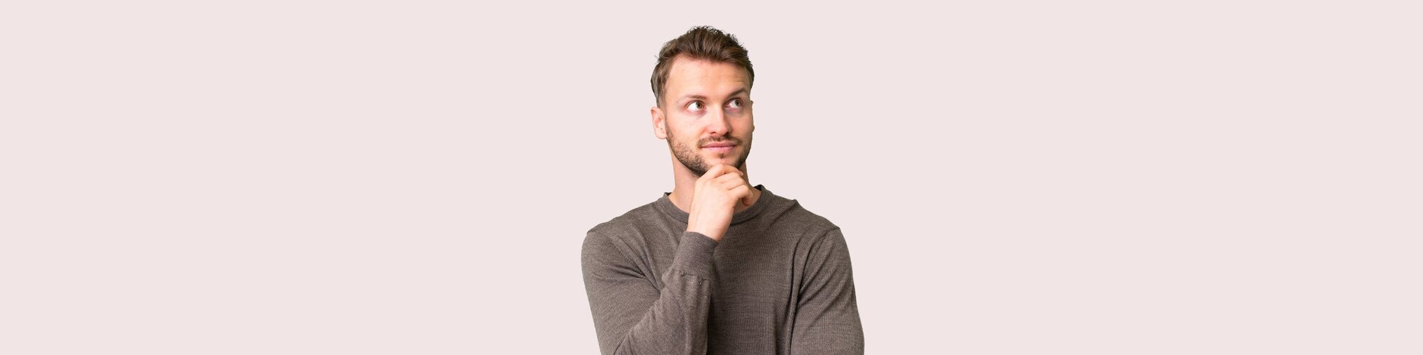 Mand i grå trøje ser tænksom ud med hånden under hagen og blikket vendt opad til siden.