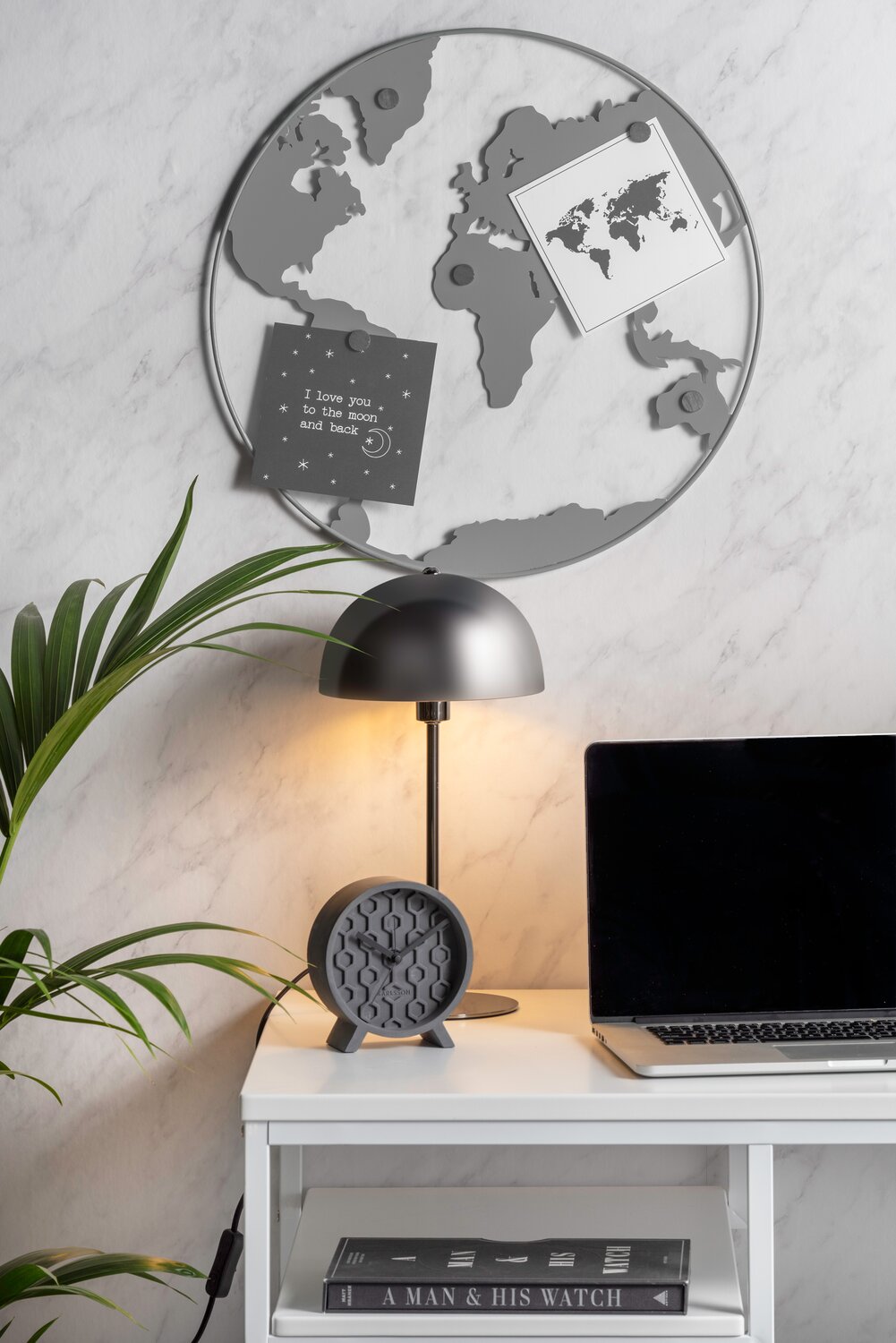 Magnettavle der ligner verdenskort foran skrivebord med lampe og computer