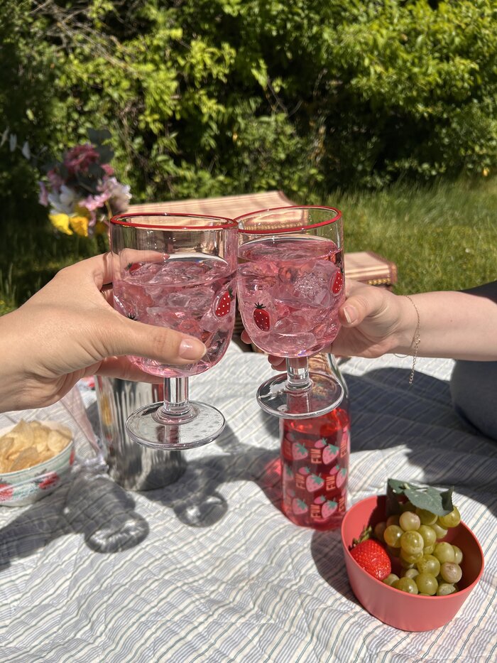 Picnic på græsset med chips, frugt og der skåles i saft i fine jordbær vinglas.