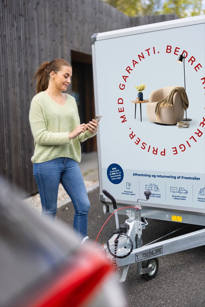 Kvinde lejer blå Daells bolighus Freetrailer via hendes mobiltelefon