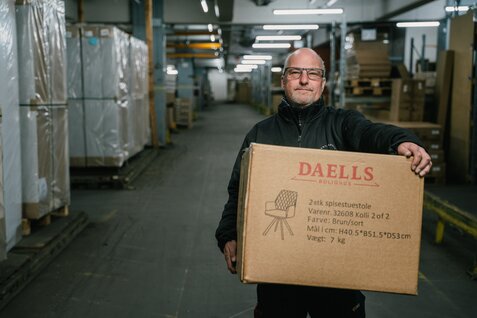 Mandlig daells medarbejder betjener kvinde ved en computer i Daells bolighus.