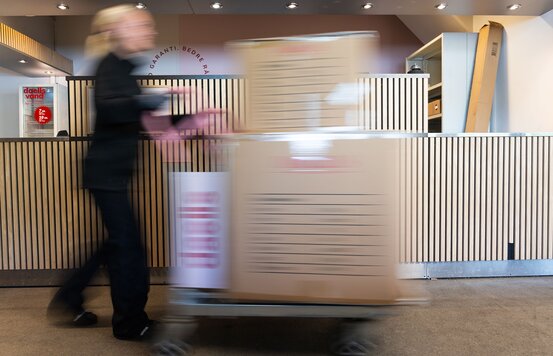 Kvindelig Daells Bolighus medarbejder kommer med varer på en vogn til udlevering.