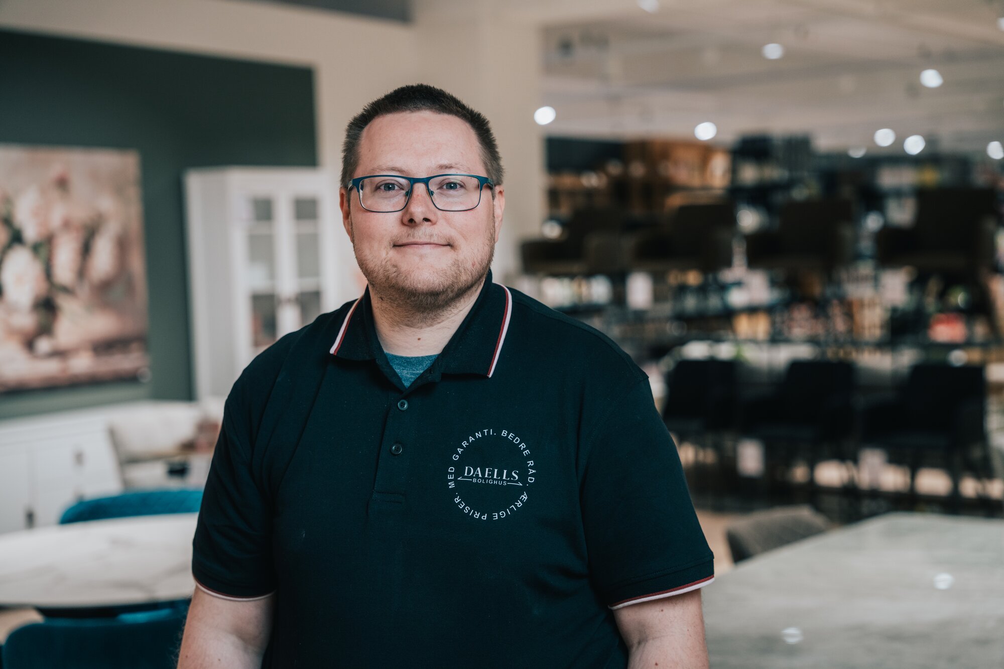 Mandlig Daells Bolighus medarbejder står i bolighuset.
