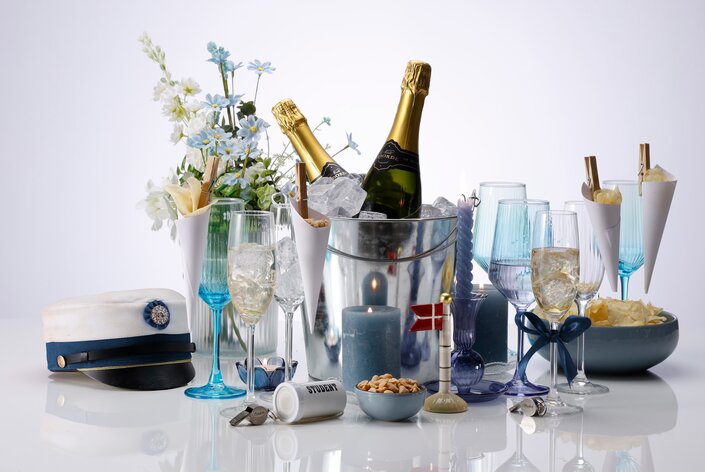 Blå studenterdækning med champagne, snacks og studenterhue til festlig fejring