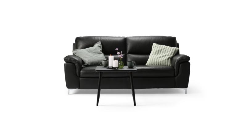 Violino Collection sort 3-personers lædersofa med polstrede armlæn, brede sædehynder og støttende ryglæn. Foran sofaen står et lille sort sofabord med to lys og en grøn vase.