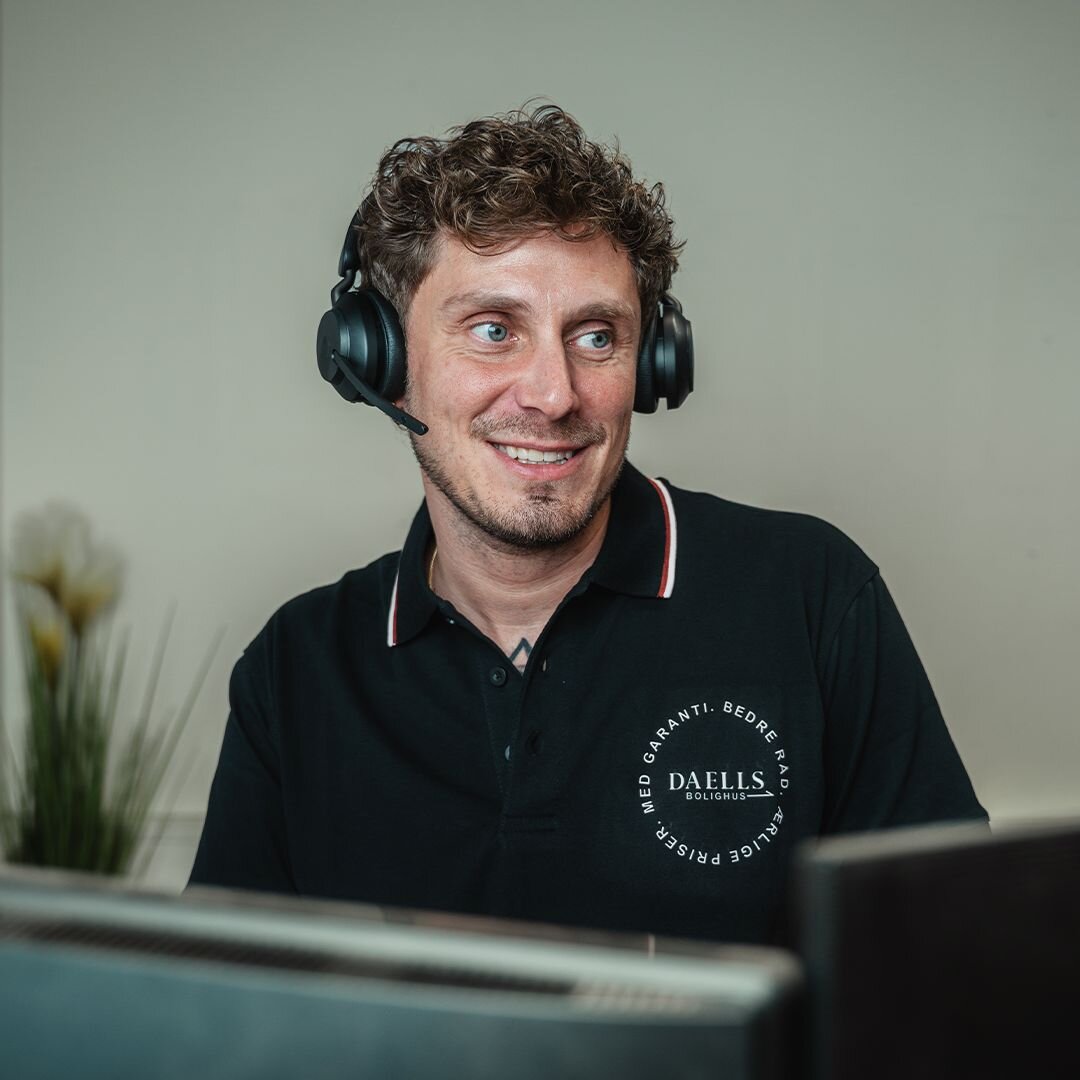Mandlig kundeservice medarbejder med headset og i sort daells polo med logo på.