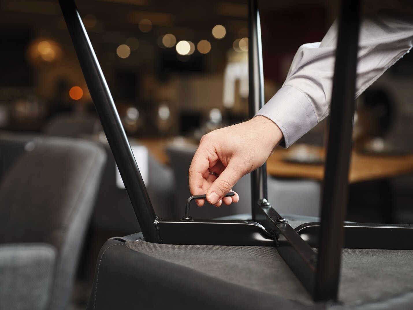 Sorte stoleben sættes på en grå spisebordsstol med en unbrakonøgle