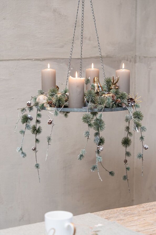 Hængende adventskrans i zink pyntet med grå bloklys og gran med kogler hængende ned fra kransen.