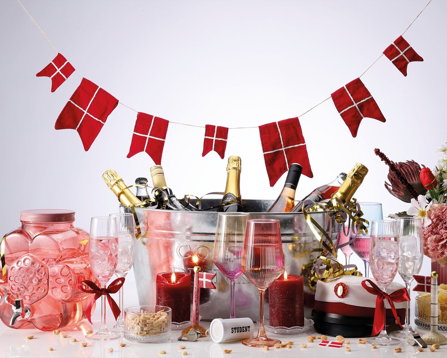 Rød studenterdækning med champagne, blomster og danske flag til festlig fejring