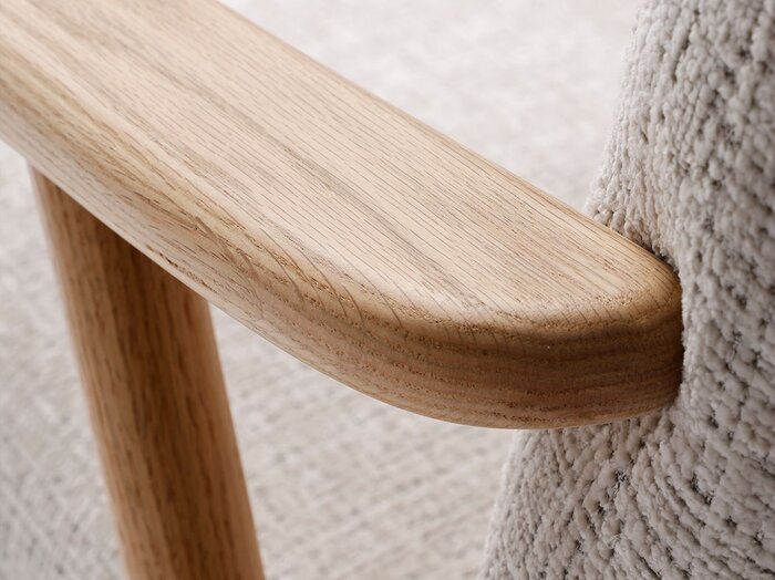 Detaljebillede af træarmlæn på en lænestole i beige møbelstof.