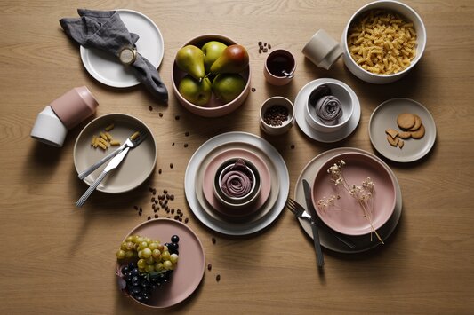 Atlas stentøjstel i sand, rosa og hvidt vist på et træbord med mad og dekoration