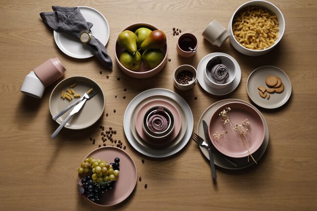 Atlas stentøjsstel i sand, rosa og hvidt vist på et træbord med mad og dekoration.