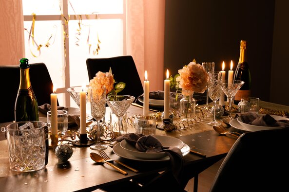 Nytårsbord dækket med gyldne detaljer, stearinlys, krystalglas og champagne – festlig borddækning med elegant stemning fra Daells Bolighus.
