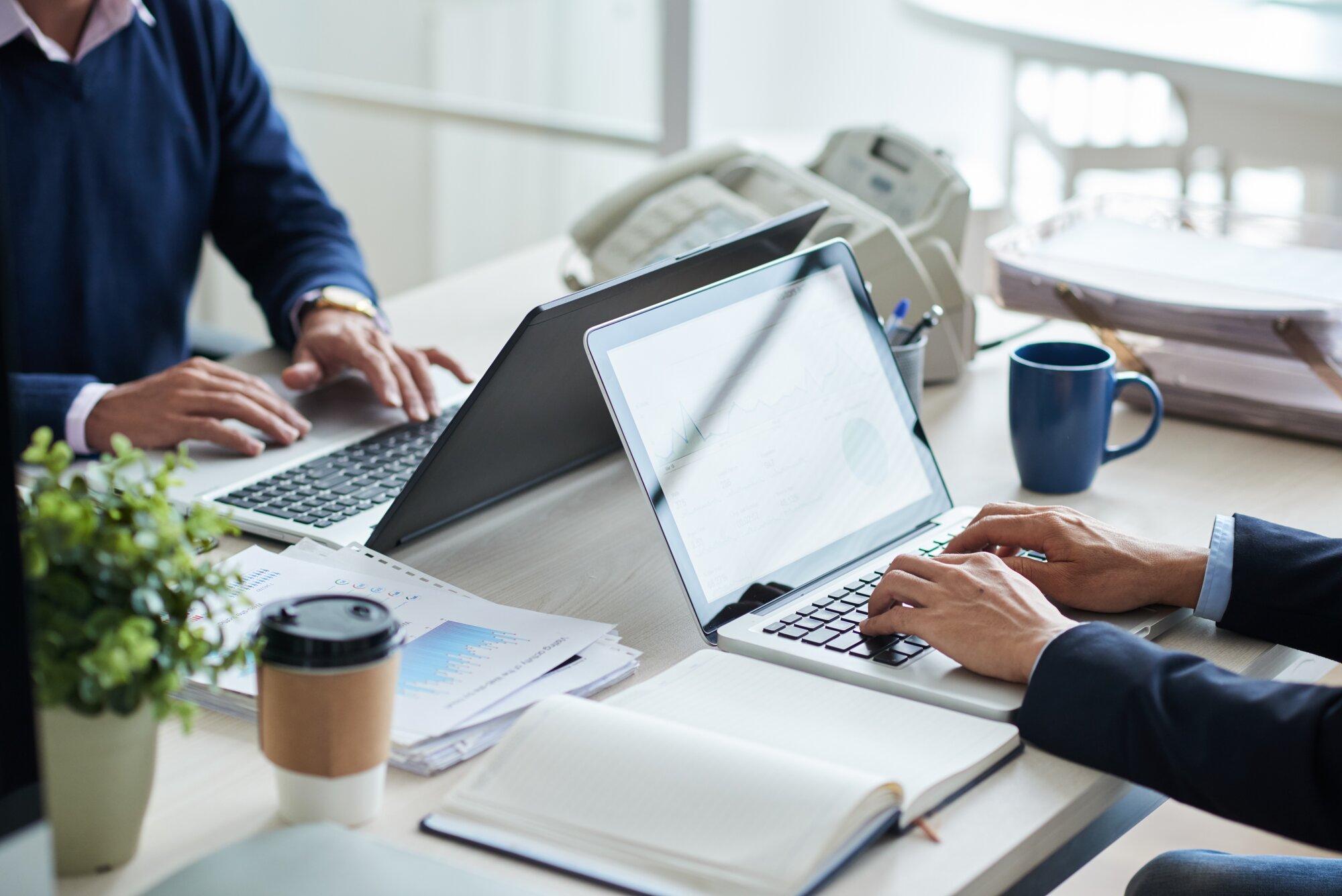 Skrivebord med to computer, som der sider to og arbejder ved