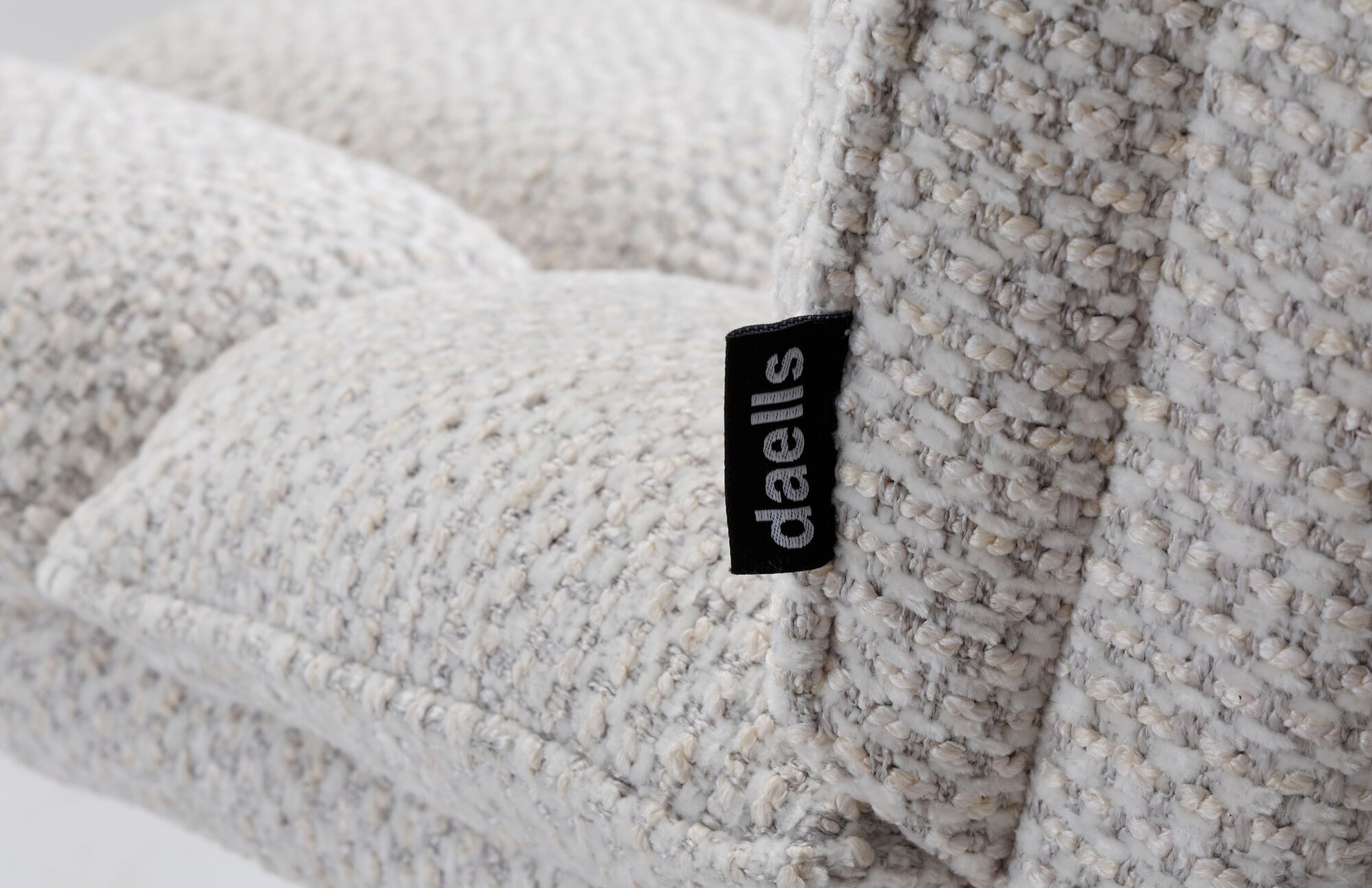 Close-up af daells private label logo på kanten af en beige farvet spisebordsstol