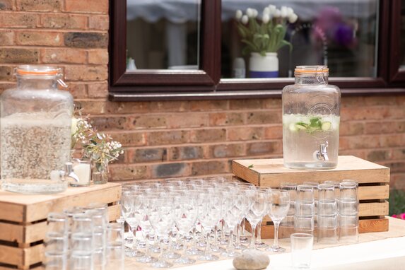 Hjemmelavet bar med dispensere til drinks på æblekasser, og glas sat op til servering.