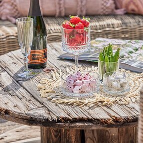 Sommerbord med champagne, samt glasskåle med elegant mønster fyldt med jordbær, ærter og skumfiduser.