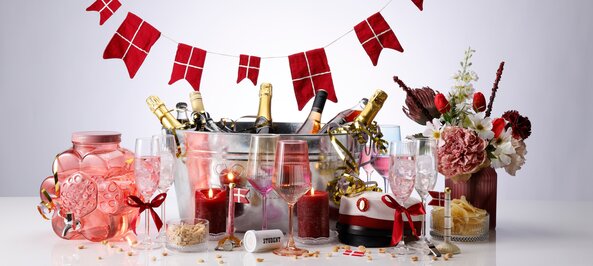 Rød studenterdækning med champagne, blomster og danske flag til festlig fejring