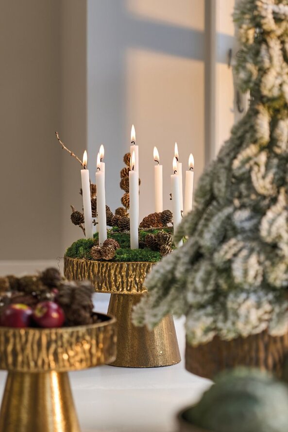 Guld dekorationsopsats med juledekoration med juletræslys, mos og kogler.