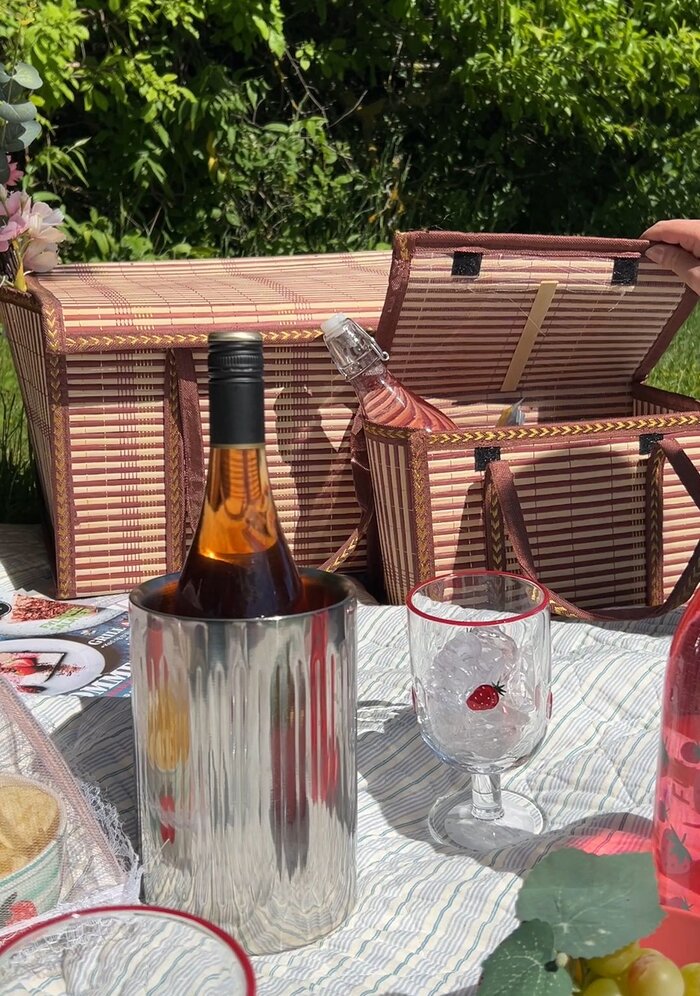 Flet picnic kurve i to størrelser på et picnictæppe dækket op med vinglas og vinkøler med rosévin.